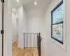 Corridor with a wealth of natural light, lofted ceiling, and light wood-type flooring