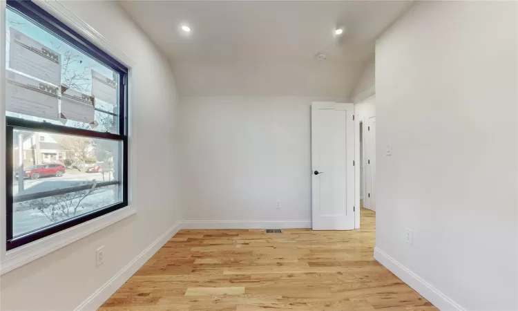 Spare room with vaulted ceiling and light wood-type flooring