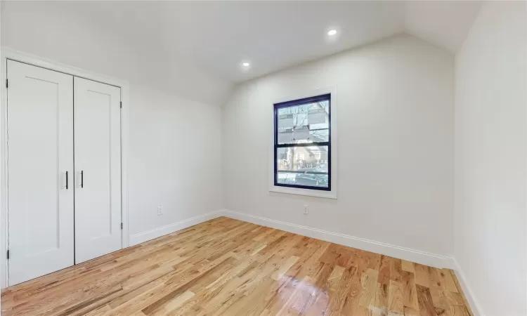 Unfurnished bedroom featuring light hardwood / wood-style floors, a closet, and vaulted ceiling