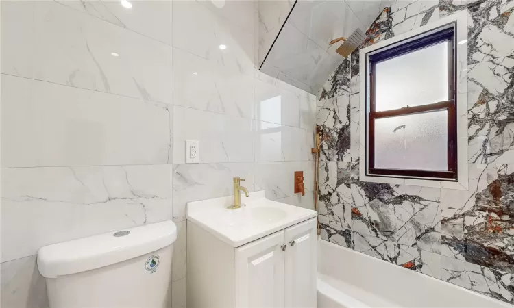 Bathroom featuring vanity, tile walls, and toilet