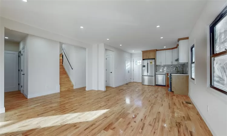 Kitchen with tasteful backsplash, stainless steel appliances, sink, light hardwood / wood-style flooring, and white cabinets