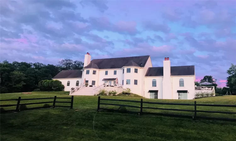 Back house at dusk featuring a lawn