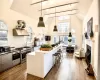 Kitchen with ventilation hood, range with two ovens, pendant lighting, a kitchen bar, and a kitchen island