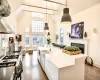 Kitchen with a center island with sink, hanging light fixtures, gas stove, french doors, and sink