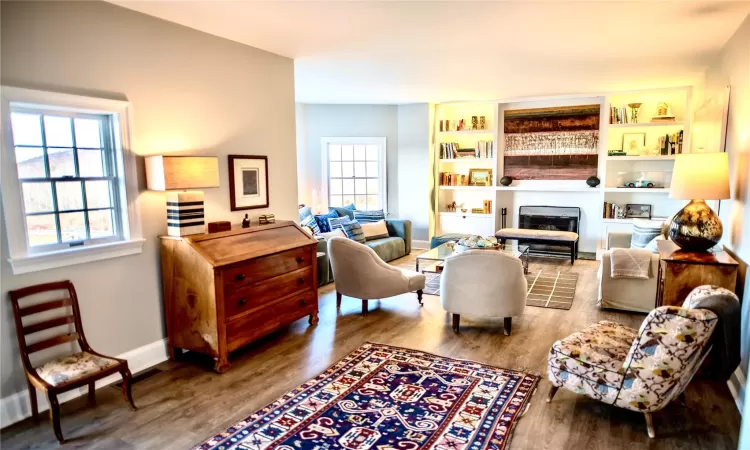 Living room featuring a fireplace, built in features, a healthy amount of sunlight, and hardwood / wood-style floors