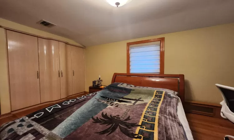 Bedroom with a closet, lofted ceiling, and dark hardwood / wood-style floors