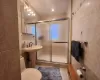 Bathroom featuring an enclosed shower, tile walls, tile patterned floors, and toilet