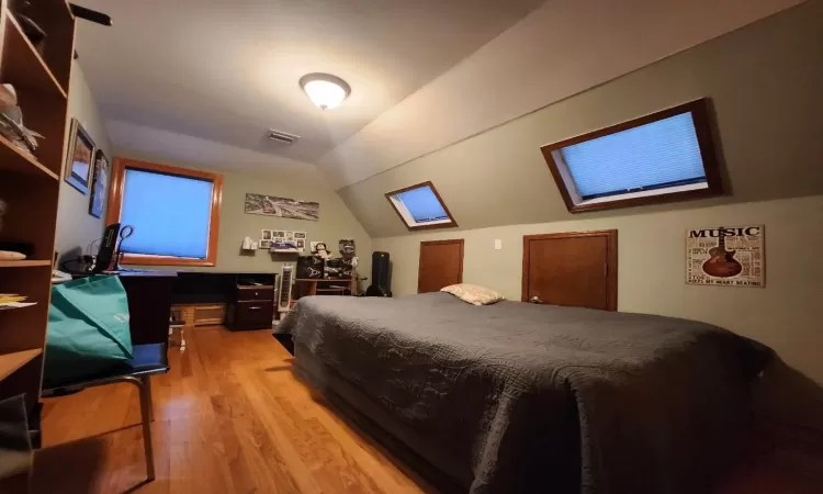 Bedroom with vaulted ceiling and hardwood / wood-style flooring