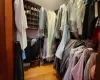 Walk in closet with light hardwood / wood-style floors