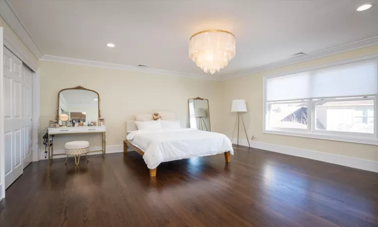 Bedroom with dark hardwood / wood-style floors, crown molding, and a chandelier