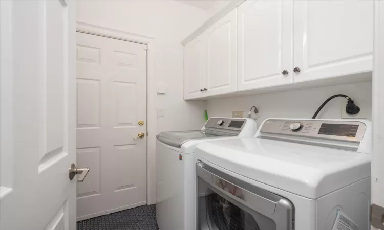 Clothes washing area featuring cabinets, washing machine and dryer, and tile patterned floors