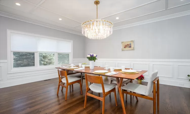 Dining area with dark hardwood / wood-style flooring, an inviting chandelier, and ornamental molding