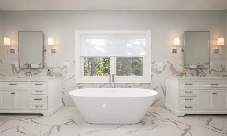 Bathroom with a tub to relax in, vanity, and tile walls