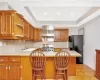 Kitchen featuring black fridge, a kitchen bar, kitchen peninsula, and wall chimney range hood