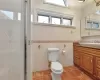 Bathroom with tile patterned flooring, a shower with door, vanity, tile walls, and toilet