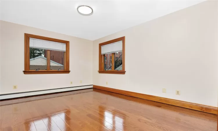 Unfurnished room featuring baseboard heating and wood-type flooring