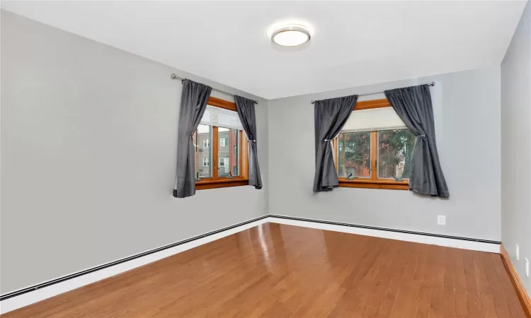 Spare room featuring baseboard heating and hardwood / wood-style floors