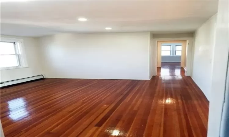 Unfurnished room with dark wood-type flooring and a baseboard heating unit