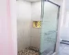 Bathroom featuring a shower with shower door, a baseboard heating unit, tile patterned floors, and toilet