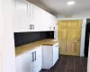 Kitchen featuring butcher block countertops, white cabinets, and tasteful backsplash