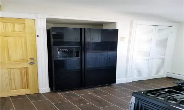 Kitchen featuring black refrigerator with ice dispenser and gas range oven