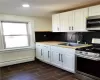 Kitchen featuring white cabinets, sink, stainless steel appliances, and a baseboard radiator