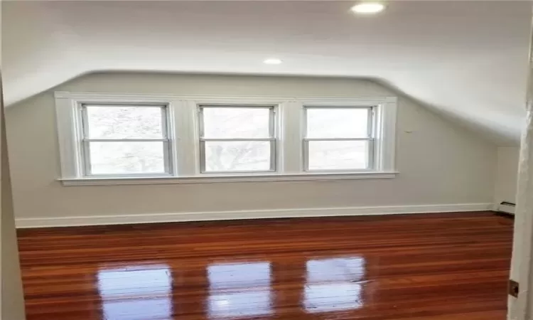 Living Room featuring dark wood-type flooring, lofted ceiling, and baseboard heating