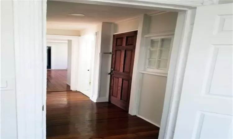 Hallway featuring dark wood-type flooring and ornamental molding