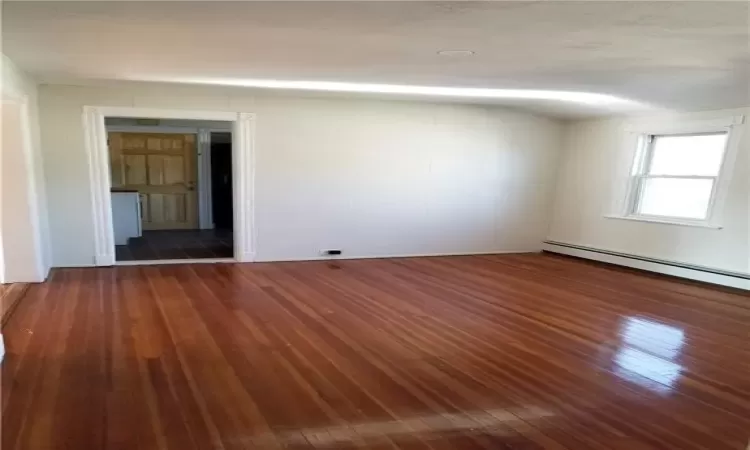 Unfurnished room with a baseboard heating unit and dark hardwood / wood-style flooring