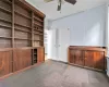 Unfurnished living room featuring ceiling fan and dark colored carpet