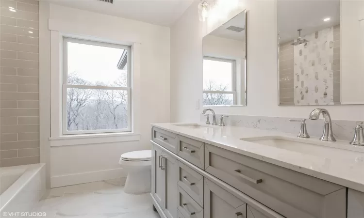 Bathroom with toilet, plenty of natural light, and vanity