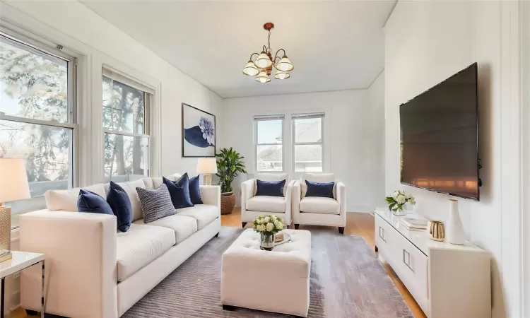 Living room with plenty of natural light, a chandelier, and wood-type flooring