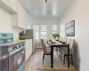 Kitchen featuring white cabinetry, appliances with stainless steel finishes, light wood-type flooring, crown molding, and radiator heating unit