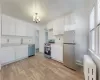 Kitchen with an inviting chandelier, white cabinetry, appliances with stainless steel finishes, radiator, and sink