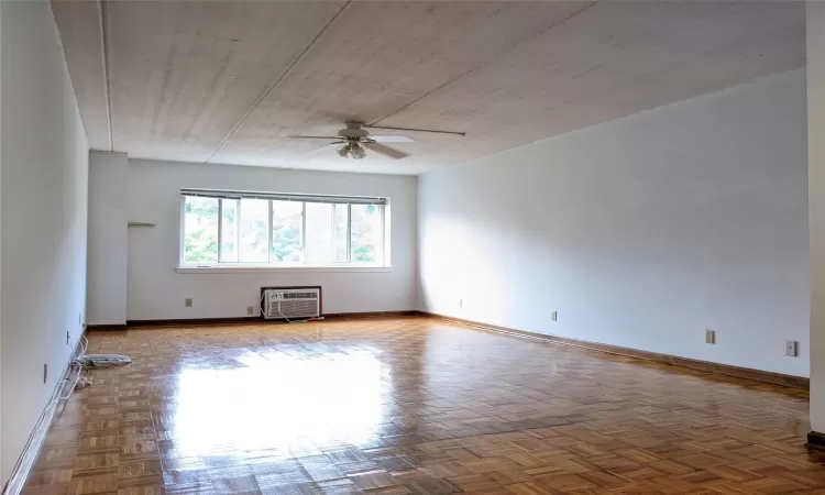 Spare room featuring parquet floors, ceiling fan, and an AC wall unit