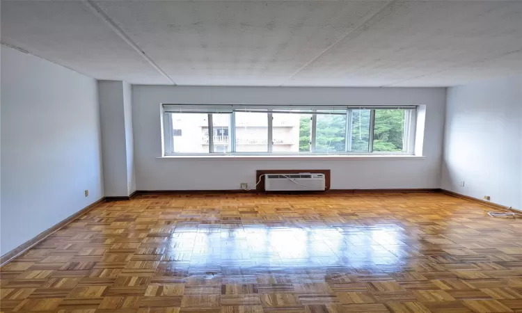 Unfurnished living room featuring a textured ceiling, parquet flooring, and a wall mounted AC