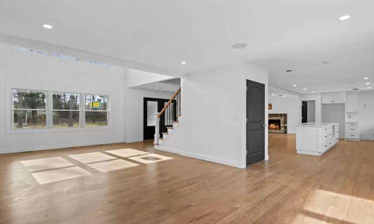 Dining space with light hardwood / wood-style floors, a high ceiling, a wealth of natural light, and a stone fireplace(Virtually Staged)