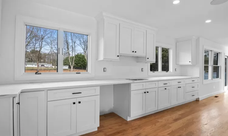 Kitchen featuring light stone countertops, a center island, light hardwood / wood-style floors, and white cabinetry