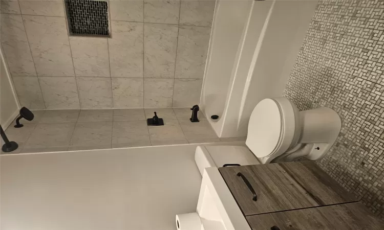 Full bathroom with toilet, tile patterned floors, tiled shower / bath, and vanity