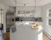 Kitchen featuring appliances with stainless steel finishes, pendant lighting, white cabinetry, and a baseboard radiator