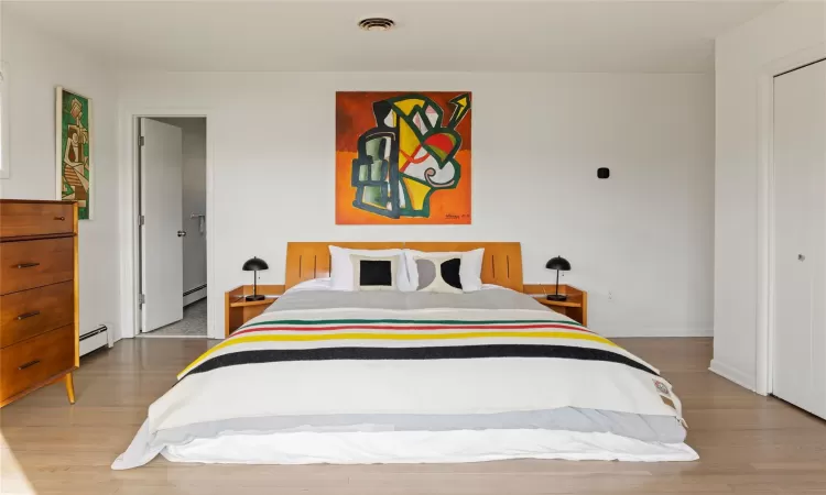 Bedroom with hardwood / wood-style flooring and a baseboard radiator