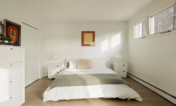 Bedroom with a baseboard radiator and wood-type flooring