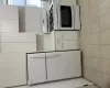 Kitchen featuring white cabinetry, light tile patterned floors, white refrigerator, and stove