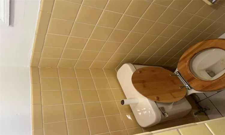 Bathroom with tile walls, toilet, and tile patterned flooring