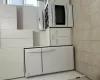 Kitchen with white fridge, light tile patterned floors, white cabinetry, and range