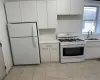 Kitchen featuring sink, white appliances, white cabinets, and light tile patterned flooring