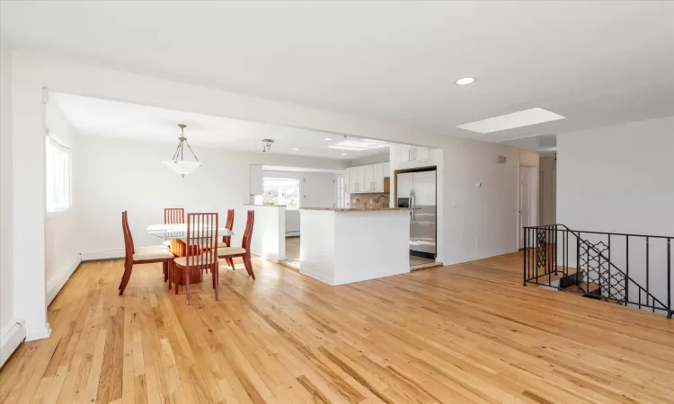 Dining area with light wood-type flooring and a skylight