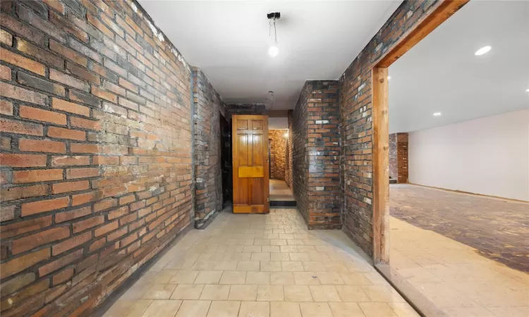 Corridor featuring brick wall