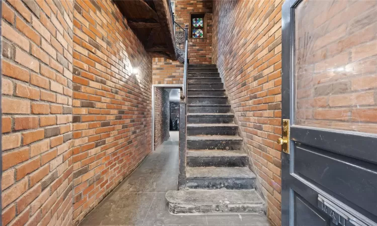 Stairway featuring brick wall