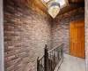 Corridor featuring a notable chandelier, brick wall, and light hardwood / wood-style flooring